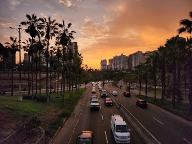 Şehir caddelerinin gün batımında birçok araç geçiyor.