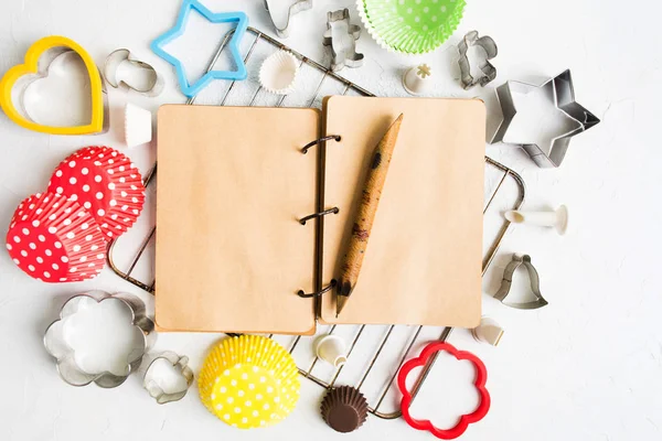 Vintage notebook malzemeleri, tarifi ve düz beyaz taş zemin üzerine çeşitli pişirme araçları ile Not için lay