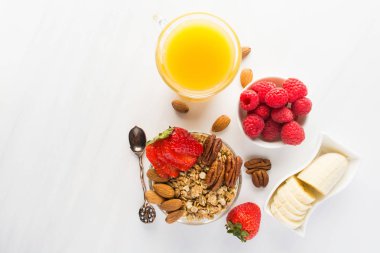 Sabah kahvaltı taze çilek, muz, kopya alanı ile beyaz tabloda granola ve portakal suyu ile