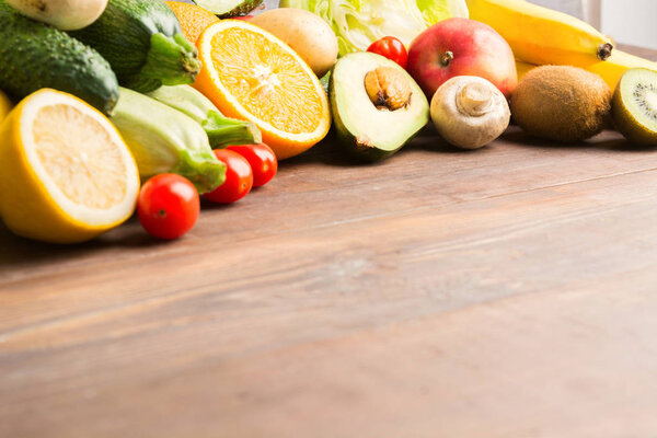 Citrus, apples and vegetables over wooden background with copy space