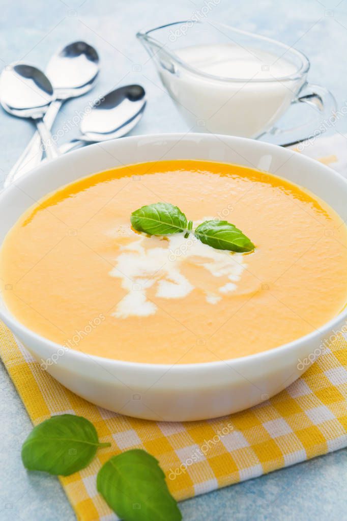 Pumpkin soup with basil on blue background, vertical shot