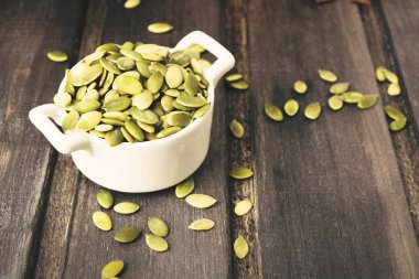 Kopya alanı, tonda fotoğraf gri ahşap zemin üzerine beyaz kase yeşil kabak çekirdeği