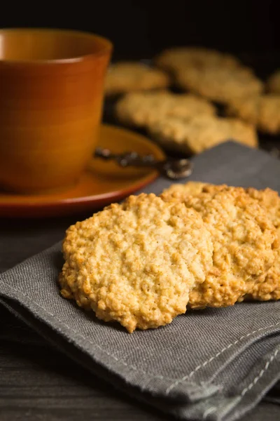 Sweet cookies with oat on tissue with tea or coffee, healthy breakfast, vertical shot