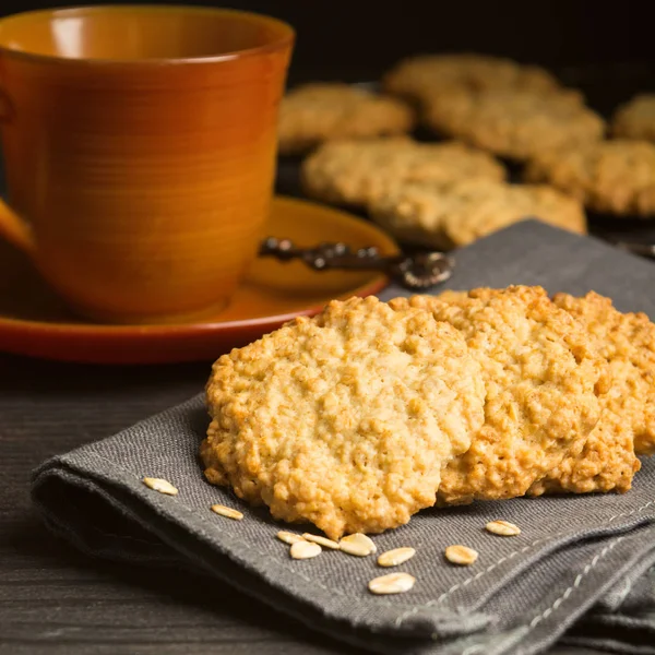 Sweet cookies with oat on tissue with tea or coffee, healthy breakfast, square shot
