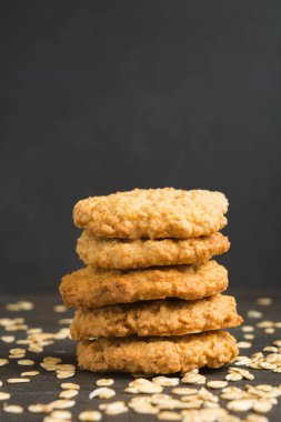 Beş yulaf ezmeli kurabiye koyu arka planda, dikey yığın halinde kopya alanı ile vurdu