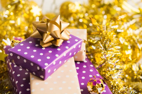 黄金のガーランドと見掛け倒しと黄金のクリスマス デコレーション リボンでエレガントなベージュと紫 パープル ギフト ボックス スタック 新年プレゼントします — ストック写真