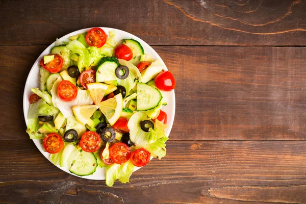 Flat lay of green and red salad with lemon and seed on wooden background with copy space