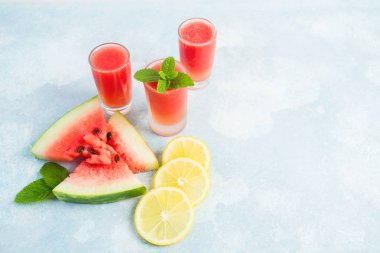 Karpuz mohito bardaklarda limon ve nane kopya alanı ile mavi arka plan üzerinde