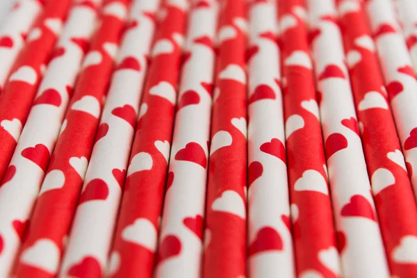 Red and white ecological plastic free paper straw with hearts, soft focus