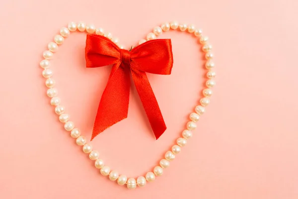 Forma Corazón Perlas Blancas Con Lazo Rojo Sobre Fondo Rosa — Foto de Stock