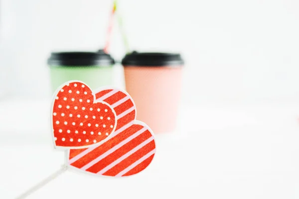 Two hearts on foreground with two beverages on background, love concept with copy space