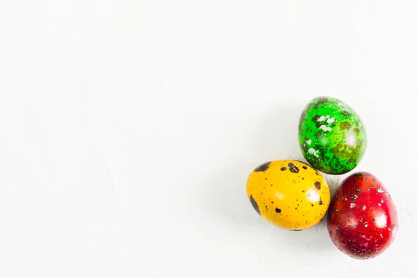 Цветные пасхальные перепелиные яйца на белом текстурированном фоне с копированием пространства — стоковое фото