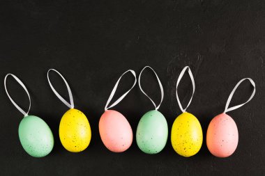 Kopya alanı ile siyah arka plan üzerinde şeritler ile renkli pastel yumurta