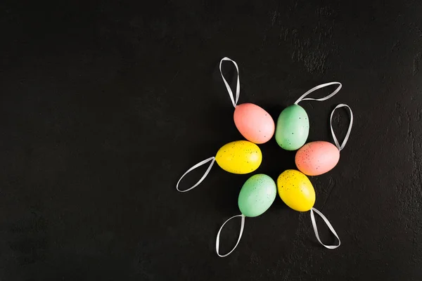 Oeufs pastel colorés de Pâques en cercle avec des rubans sur le dos fond en béton texturé avec espace de copie — Photo