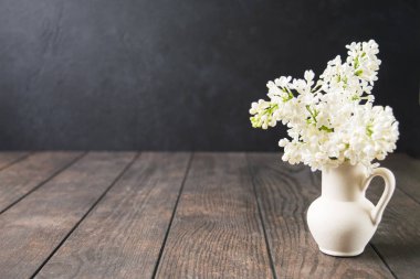 Ahşap masada beyaz leylak çiçekli beyaz seramik vazo. Spa baharı ya da yaz aromaterapi konsepti. Model yap. Boşluğu kopyala