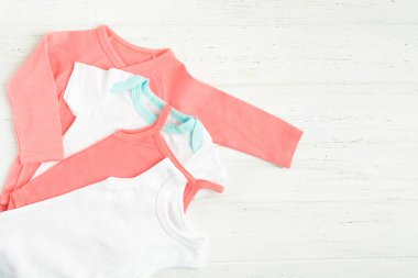 Beyaz ahşap arka plan üzerinde bebek bodysuit giysiler. Kopya alanı. Düz döşeme stili