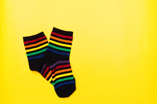 Calcetines de algodón textil negro con patrón de rayas de colores brillantes sobre fondo amarillo — Foto de Stock