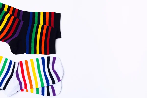 Twee witte en zwarte paar sokken met kleurrijke gestreepte patroon voor voeten. Modieuze schone katoenen kleding met grappige print. Top View — Stockfoto