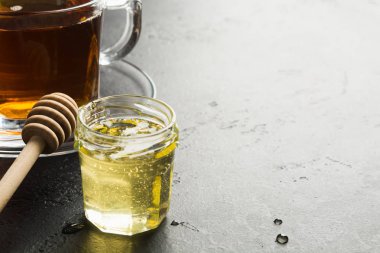 Koyu arka planda ahşap sopa ile çay ile cam kavanoz çiçek ışık organik bal