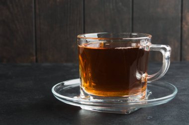 Siyah taş masa ve ahşap duvar üzerinde uçan ile aroma siyah çay bir bardak fincan