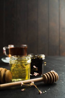 Siyah taş ve kopya alanı ile ahşap arka plan üzerinde ahşap sopa ile cam kavanozlarda koyu ve hafif bilemek. Soğuk algınlığı için tedavi için sağlıklı organik doğal gıda