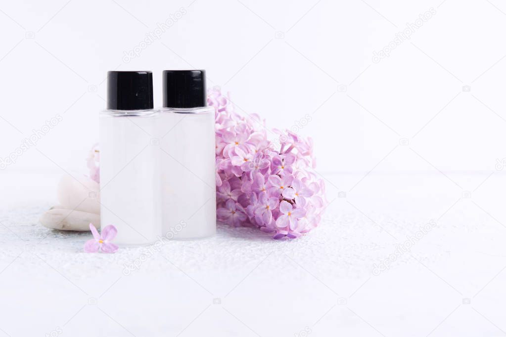 Two plastic bottle with shower gel or shampoo for bath with lilac aroma and natural flowers. Spa concept