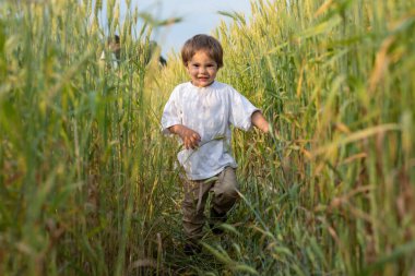 Küçük çocuk çimlerin arasından geçiyor.