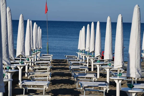 Kumsalda, beyaz şezlonglar arasında bir patika.