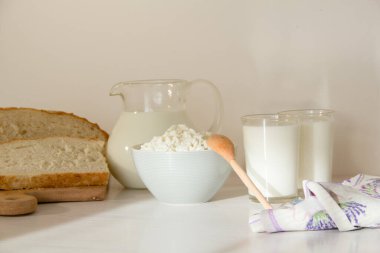Cam kavanozda süt, masada süzme peynir ve ekmek. Beyaz arkaplan.