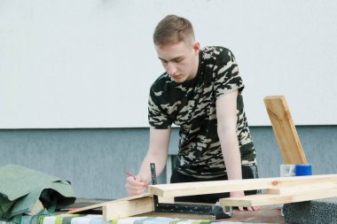 Marangoz ahşap tabakla çalışıyor. Marangoz ahşap kalasla çalışıyor. Genç adam evinin yakınında çalışıyor.. 