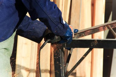 Adam evinin dışında çalışıyor. Tamirci öğütme makinesi kullanır ve ölçümler yapar. Açı öğütücü kullanılıyor.