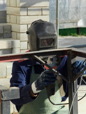 Adam evinin dışında çalışıyor. Tamirci öğütme makinesi kullanır ve ölçümler yapar. Açı öğütücü kullanılıyor.