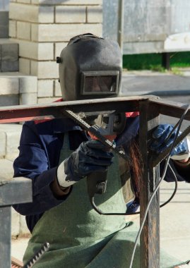 Adam evinin dışında çalışıyor. Tamirci öğütme makinesi kullanır ve ölçümler yapar. Açı öğütücü kullanılıyor.