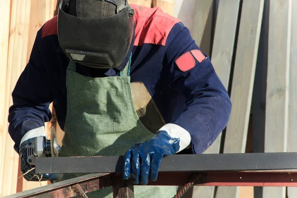 Adam evinin dışında çalışıyor. Tamirci öğütme makinesi kullanır ve ölçümler yapar. Açı öğütücü kullanılıyor.