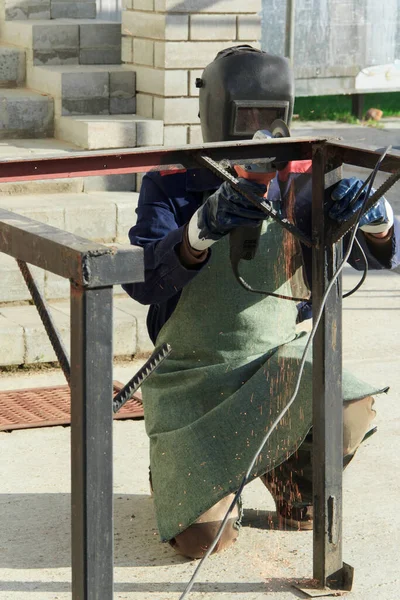 The man works outside his house. Handyman uses a grinding machine and makes measurements. Using angle grinder.