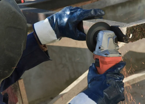 The man works outside his house. Handyman uses a grinding machine and makes measurements. Using angle grinder.