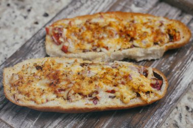 Peynir ve diğer karmaşık dolgu ile geleneksel Fransız bölünmüş baget bir çift. Ahşap retro arka plan standı tepsisinde.