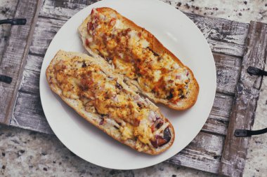 Peynir ve diğer karmaşık dolgu ile geleneksel Fransız bölünmüş baget bir çift. Ahşap retro arka plan standı tepsisinde.