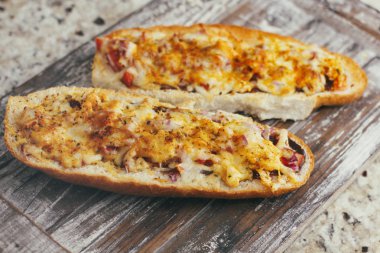 Peynir ve diğer karmaşık dolgu ile geleneksel Fransız bölünmüş baget bir çift. Ahşap retro arka plan standı tepsisinde.