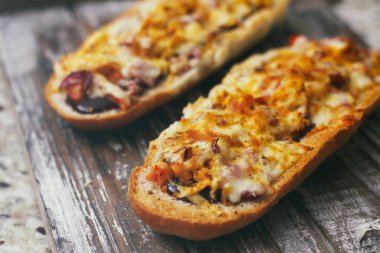 Peynir ve diğer karmaşık dolgu ile geleneksel Fransız bölünmüş baget bir çift. Ahşap retro arka plan standı tepsisinde.