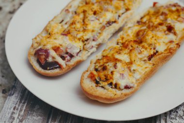 Peynir ve diğer karmaşık dolgu ile geleneksel Fransız bölünmüş baget bir çift. Ahşap retro arka plan standı tepsisinde.