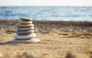 Bulanık deniz zemininde kaplıca taşlarının Zen piramidi. Kumsalda kum. Deniz kıyısında. Su dalgaları dokusu. Fotoğrafın sol tarafı. Metin için yer. 