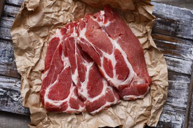 Ahşap masa arka plan üzerinde pişirme kağıdı üzerinde dilimlenmiş taze çiğ et. Domuz boynunu doğrayın. 