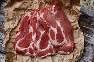 Ahşap masa arka plan üzerinde pişirme kağıdı üzerinde dilimlenmiş taze çiğ et. Domuz boynunu doğrayın. 