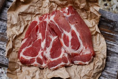 Ahşap masa arka plan üzerinde pişirme kağıdı üzerinde dilimlenmiş taze çiğ et. Domuz boynunu doğrayın. 