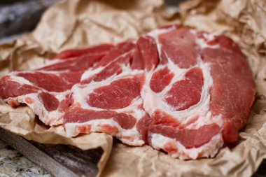 Pişirme kağıdı ve ahşap masa üzerinde taze çiğ dilimlenmiş et.