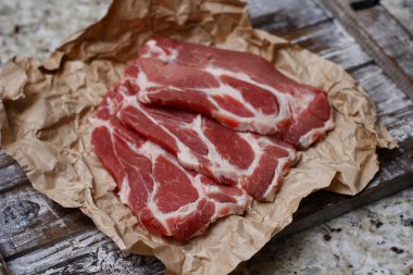 Pişirme kağıdı ve ahşap masa üzerinde taze çiğ dilimlenmiş et.