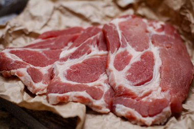 Pişirme kağıdı ve ahşap masa üzerinde taze çiğ dilimlenmiş et.