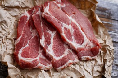 Pişirme kağıdı ve ahşap masa üzerinde taze çiğ dilimlenmiş et.