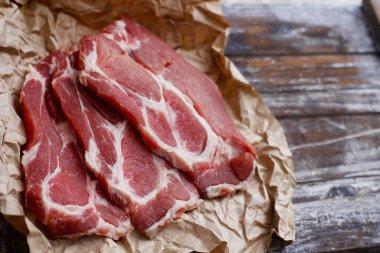 Ahşap masa arka plan üzerinde pişirme kağıdı üzerinde dilimlenmiş taze çiğ et. Domuz boynunu doğrayın. 